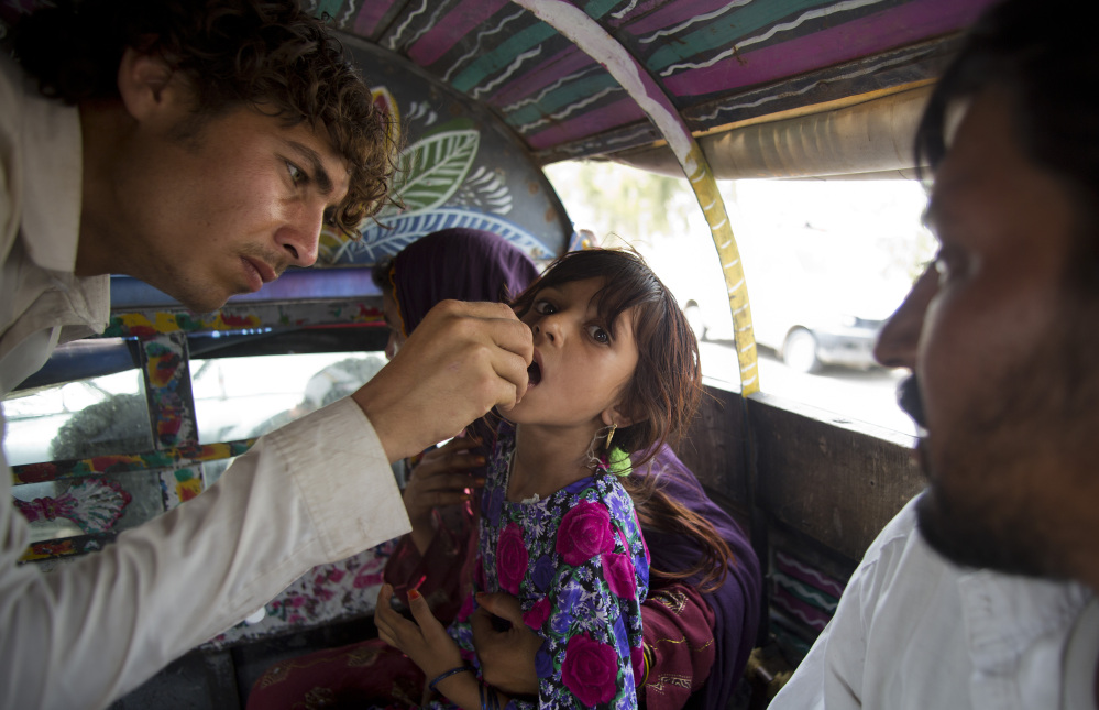 A Pakistani volunteer gives the polio vaccine to a displaced girl in Bannu. North Waziristan became a hotbed of polio infections after the Taliban banned immunizations.