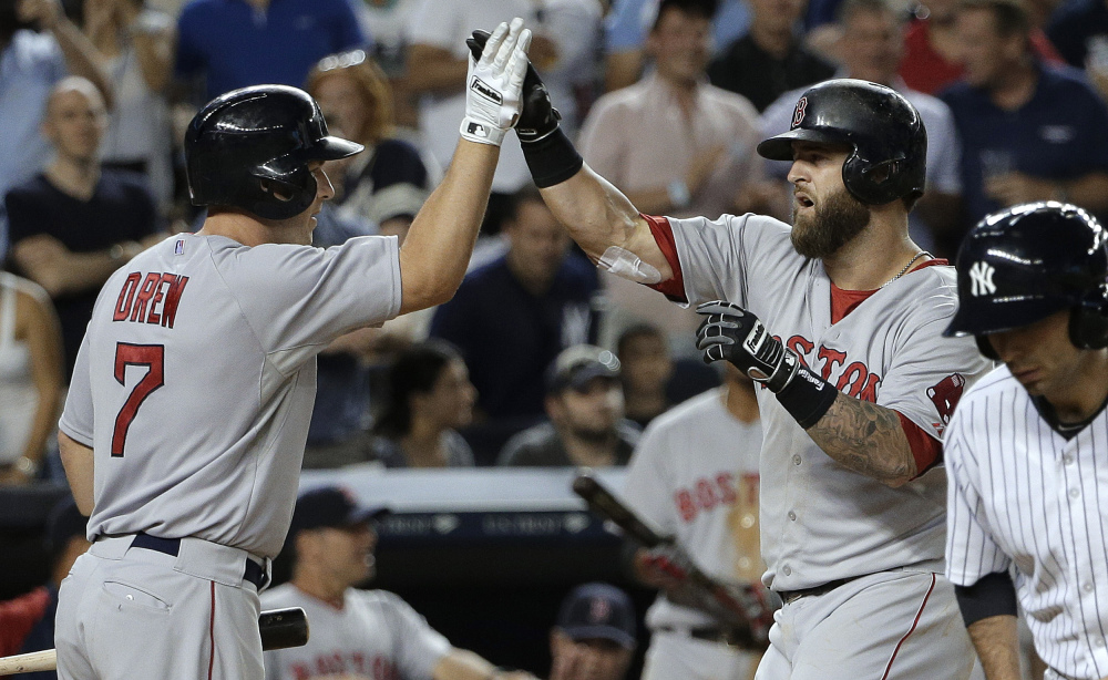 Boston’s Mike Napoli, right, is greeted by Stephen Drew at home plate after hitting a solo home run against the New York Yankees in the ninth inning Saturday  in New York. The Red Sox won 2-1.