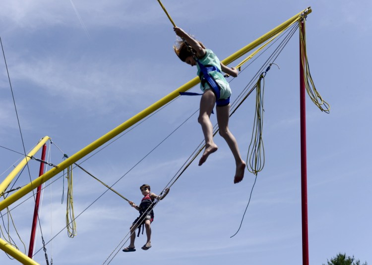 Holiday Adams, 11, and her brother Cash Adams, 8, jump on the trampoline at La Kermesse in Biddeford on Saturday. The 32nd annual Franco-American festival continues through Sunday at the Biddeford Intermediate School field on Hill Street.