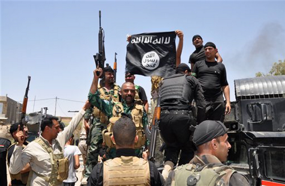 Iraqi security forces hold up a flag of the Islamic State in Iraq and the Levant they captured during an operation to regain control of Dallah Abbas north of Baqouba, the capital of Iraq’s Diyala province, 35 miles northeast of Baghdad. The Islamic State, which already controls vast swaths in northern and eastern Syria amid the chaos of that nation’s civil war, aims to erase the borders of the modern Middle East and impose its strict brand of Shariah law.