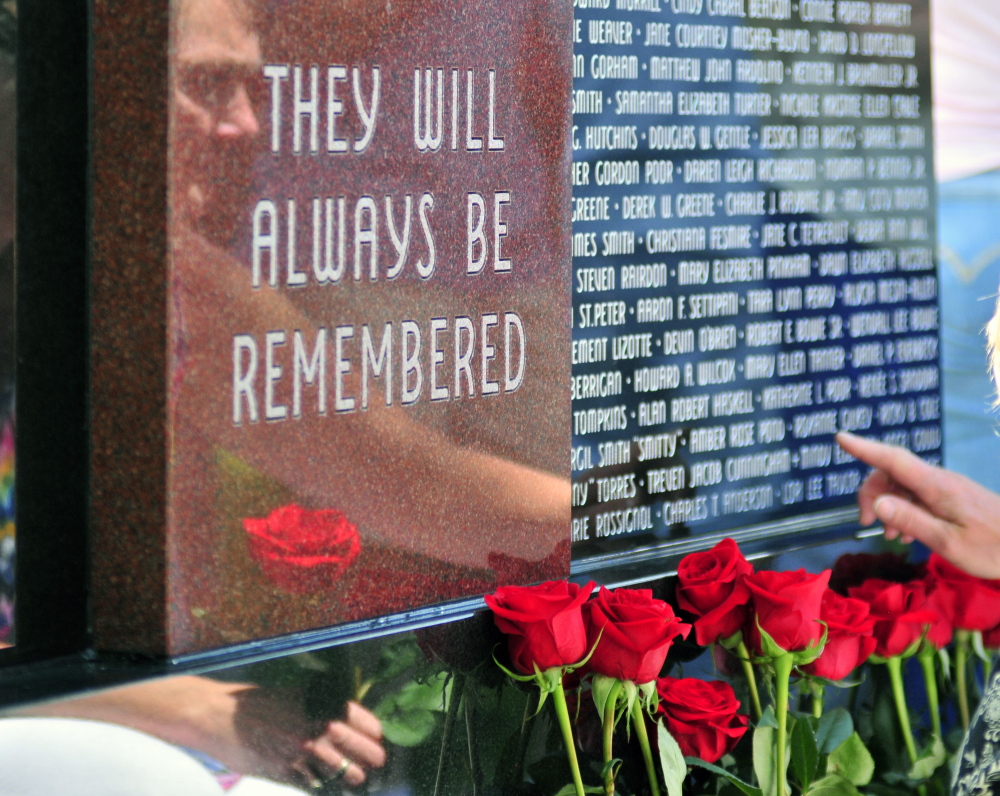 Survivors place roses in front of the Maine Murder Victims’ Memorial Monument at the end of the dedication ceremony. 