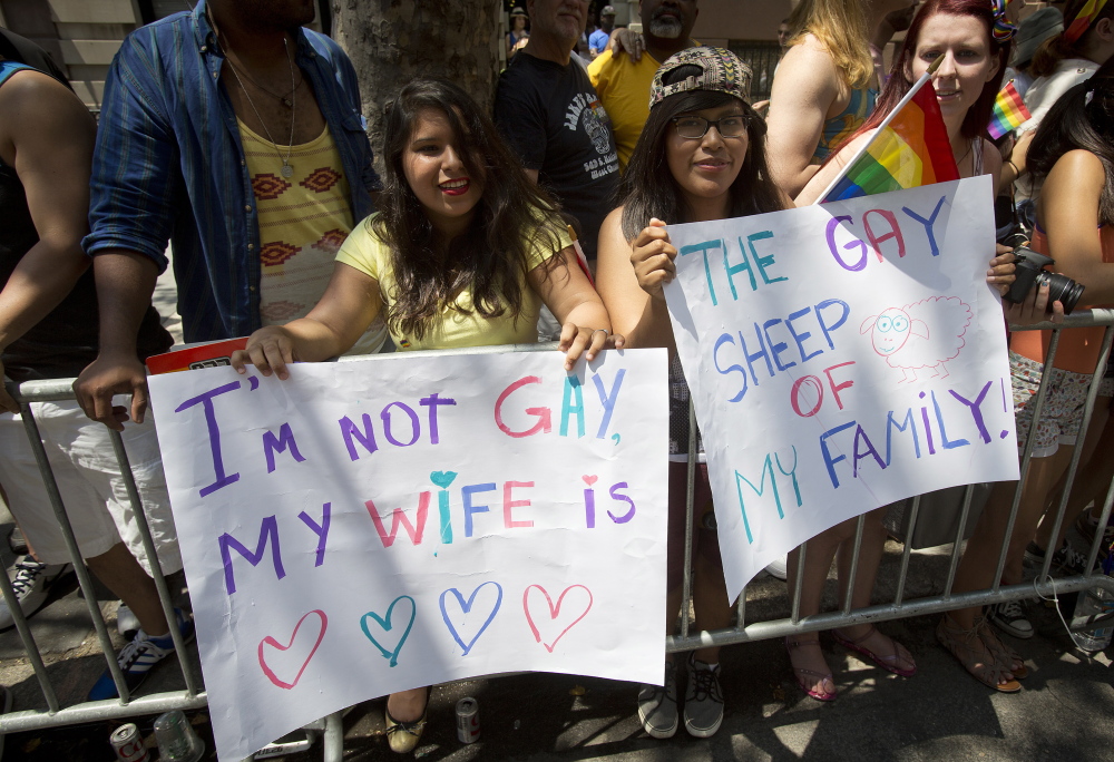 Spectators hold placards as they watch the annual Gay Pride Parade on Christopher Street in  Manhattan on Sunday.