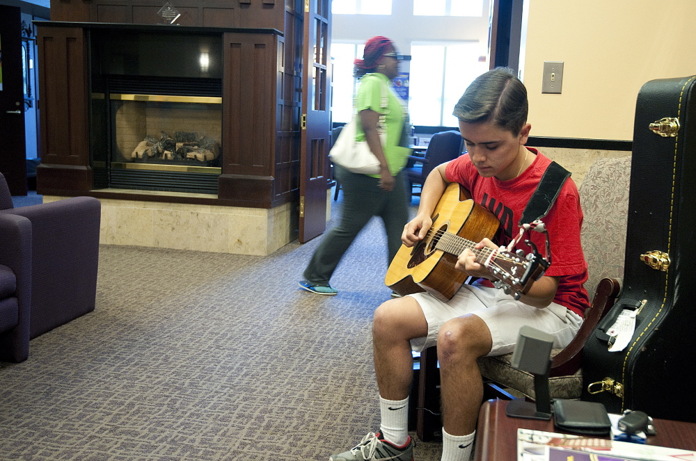 Nick Moniz, 17, of Naugatuck, Conn., plays guitar in the lobby of the Harold Leever Regional Cancer Center in Waterbury, Conn. Moniz played music as part of a community service project and liked it so much he is doing it during his free time in the summer.