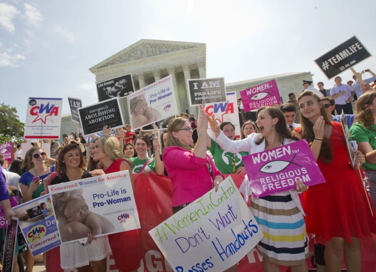 Demonstrators react to hearing the Supreme Court’s decision on the Hobby Lobby case outside the Supreme Court in Washington, Monday.