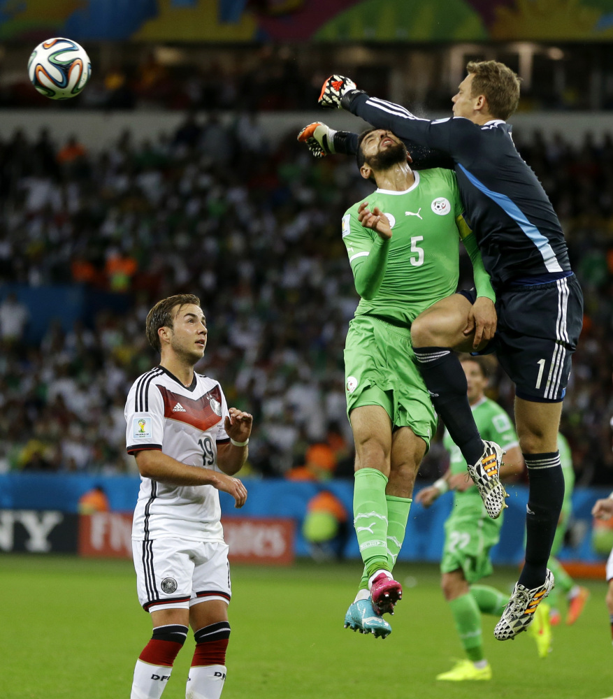 Germany’s goalkeeper Manuel Neuer. right, punches the ball away from Algeria’s Rafik Halliche during the World Cup round of 16 soccer match between Germany and Algeria.