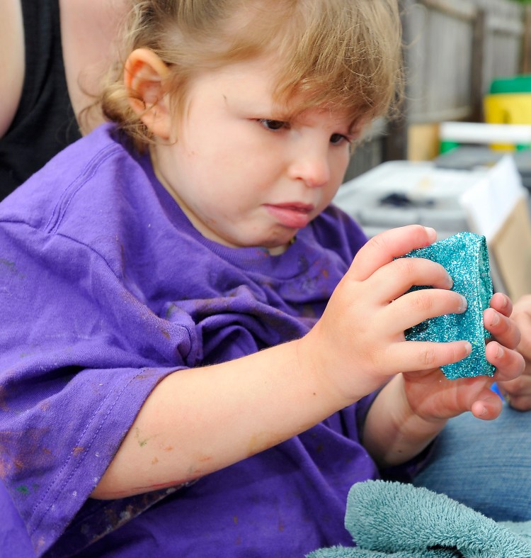 Tess Bigelow, 4, explores a wrist band made by art students from the University of Southern Maine to help young children explore textures and colors and use their dexterity  at Children's Odyssey pre-school in Portland on Thursday.