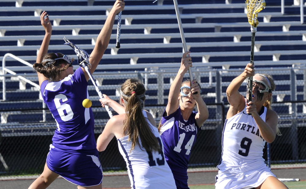 John Patriquin/Staff Photographer Emily Krabbe, left, and Micary Verville of Deering compete for the lacrosse ball with Merritt Ryan, 13, and Hallie Allex of Portland during Portland’s 19-12 victory Tuesday at Fitzpatrick Stadium. The Bulldogs improved to 6-6 heading to the Eastern Class A tournament.