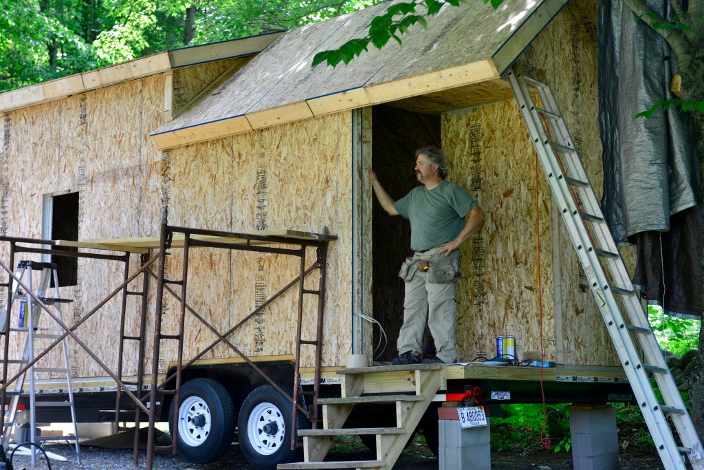 Alan Plummer works on his tiny house in his mother’s driveway in Manchester. Plummer says he plans to start a tiny house community in rural Maine in the next few years. Logan Werlinger/Staff Photographer