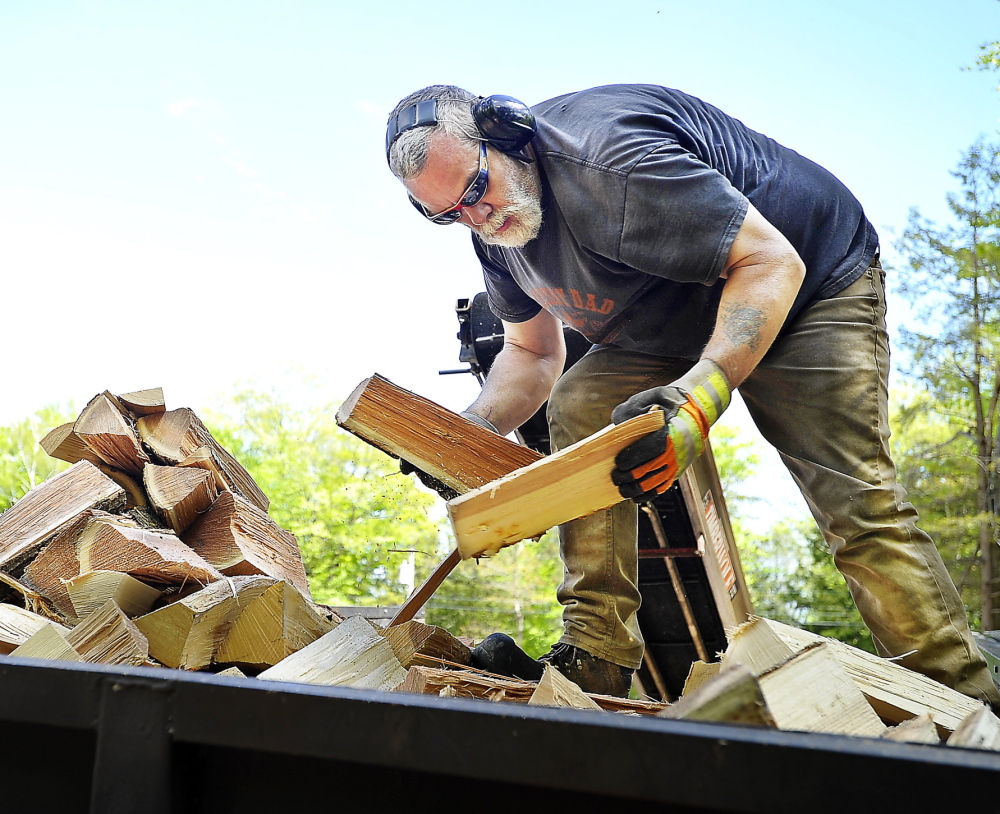 Mark Killinger, owner of Atlantic Firewood, arranges processed firewood in the bed of his truck in Windham on May 21. He and other dealers are receiving larger and earlier orders this year. Gordon Chibroski/Staff Photographer