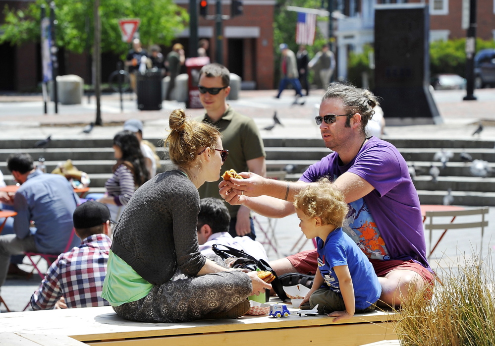 On a sun-soaked day in Congress Square Plaza in Portland, Michael Gatlin offers a bite of a sandwich to Bonnie Durham while their son, Ovid, 2, plays next to them. Gatlin and Durham said they plan to vote June 10 against the referendum making it harder to sell public spaces.