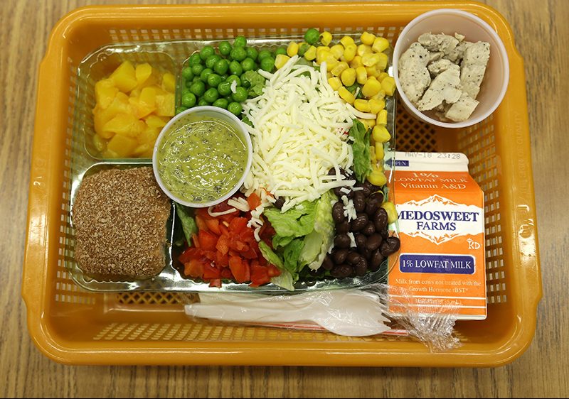 In this file photo, a school lunch salad entree option featuring low-sodium chicken, a whole-grain roll, fresh red peppers, and cilantro dressing is assembled in a lunch basket at Mirror Lake Elementary School in Federal Way, Wash., south of Seattle.