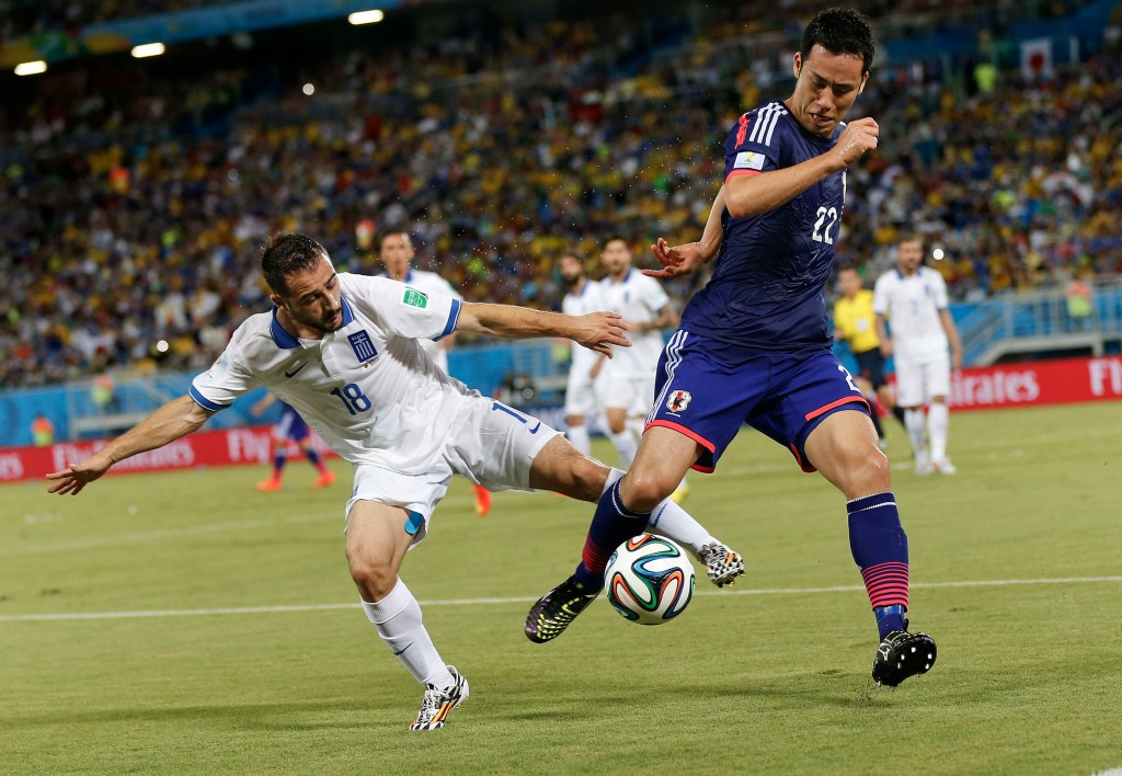 Greece's Giannis Fetfatzidis, left, challenges Japan's Maya Yoshida during the group C World Cup soccer match between Japan and Greece at the Arena das Dunas in Natal, Brazil, Thursday, June 19, 2014.