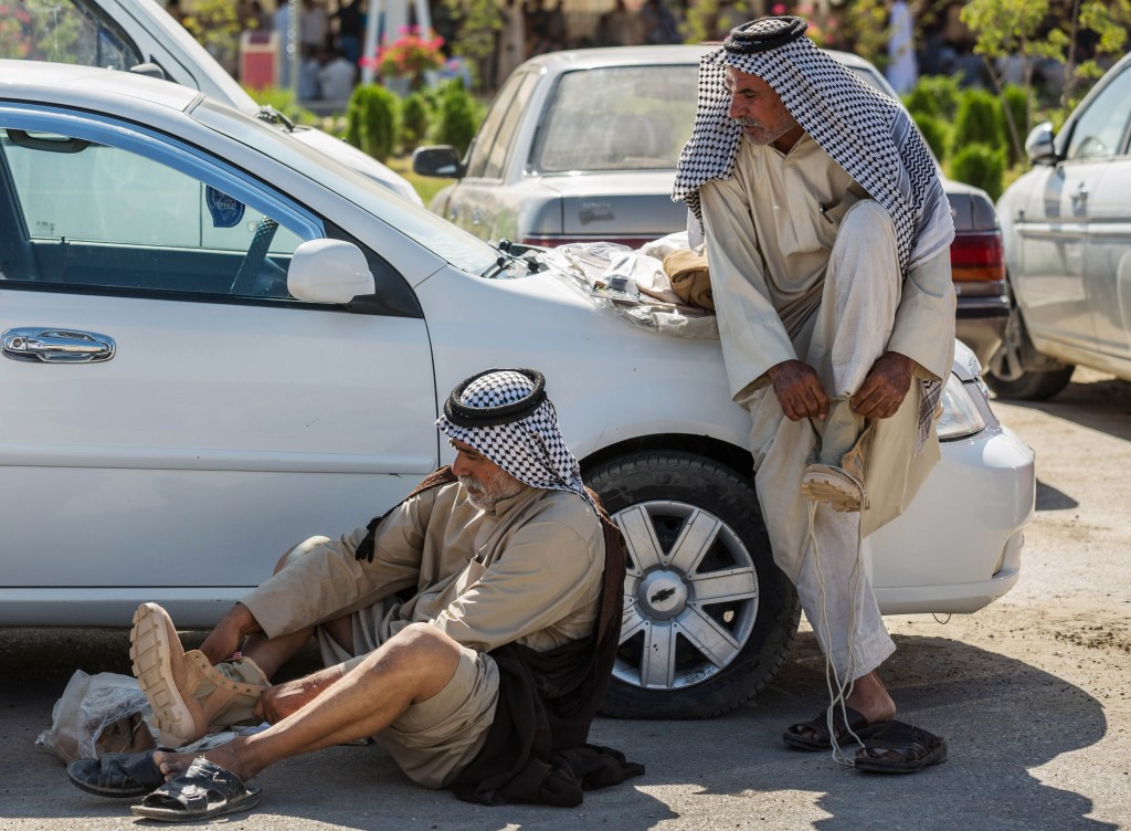 Members of an Iraqi volunteer force put on their newly issued boots in the Shiite holy city of Karbala, 50 miles (80 kilometers) south of Baghdad, Iraq, Tuesday, June 24, 2014.