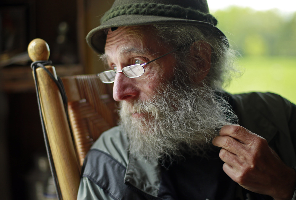 Burt Shavitz pauses during an interview in May to watch a litter of fox kits play near his camp in Parkman. The reclusive beekeeper whose simple life became complicated by his status as a corporate icon is now the subject of a documentary, “Burt’s Buzz,” which opens Friday. The Associated Press/Robert F. Bukaty 