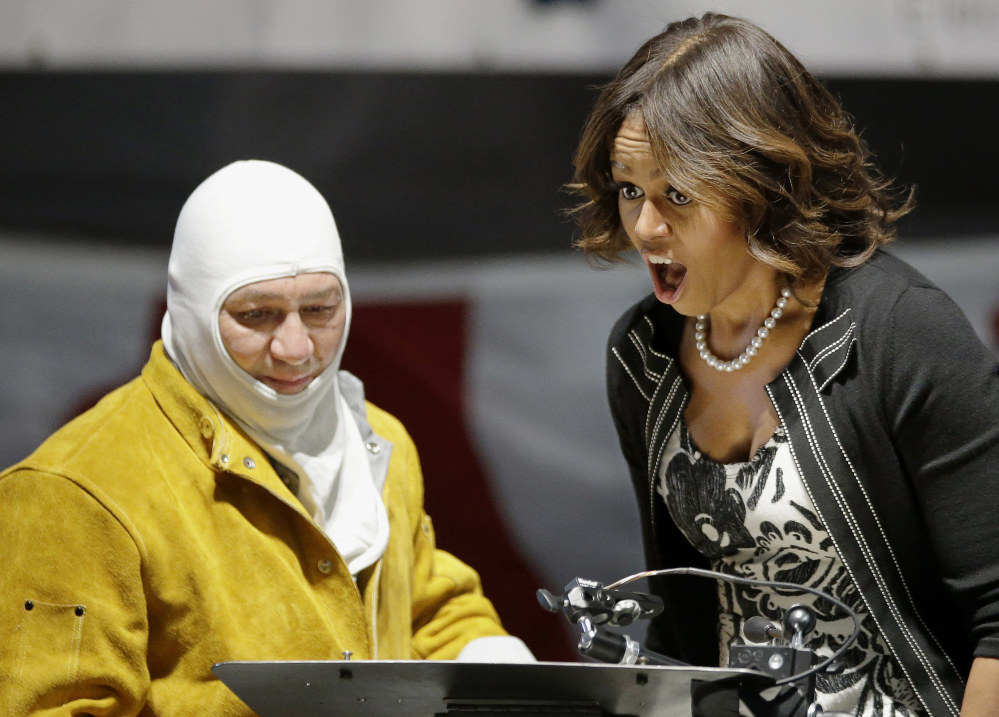 First lady Michelle Obama reacts to seeing her initials welded onto a steel plate by welder Michael Macomber during a keel-laying ceremony for a submarine that will become the USS Illinois on Monday in North Kingstown, R.I. The Associated Press