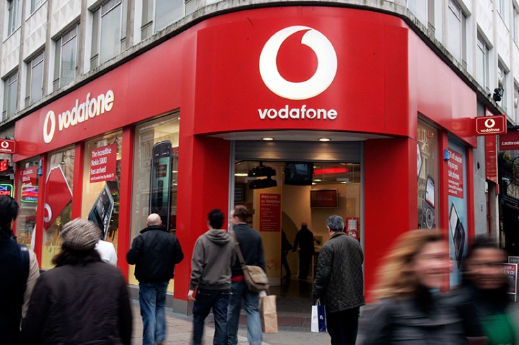 In this 2009 file photo, people walk by a Vodafone branch in central London. The Associated Press