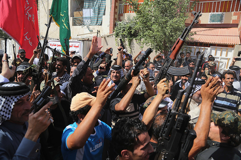 Iraqi Shiite tribal fighters raise their weapons and chant slogans against the al-Qaida inspired Islamic State of Iraq and the Levant (ISIL) in Baghdad's Sadr city, Iraq, Saturday.