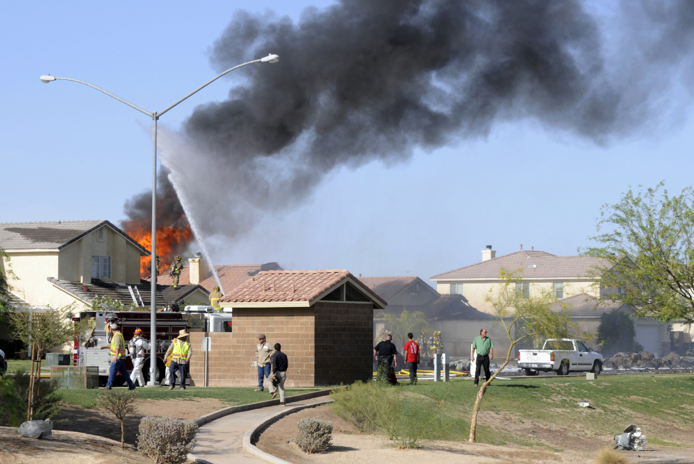Smoke and flames rise after a Marine jet crashed into a residential area in the desert community of Imperial, Calif., setting two homes on fire Wednesday, June 4, 2014. The pilot ejected safely, and there was no immediate word of any injuries on the ground. The Harrier AV-8B went down at 4:20 p.m. in Imperial, a city of about 15,000 near the U.S.-Mexico border about 90 miles east of San Diego. (AP Photo/Imperial Valley Press, Chelcey Adami)