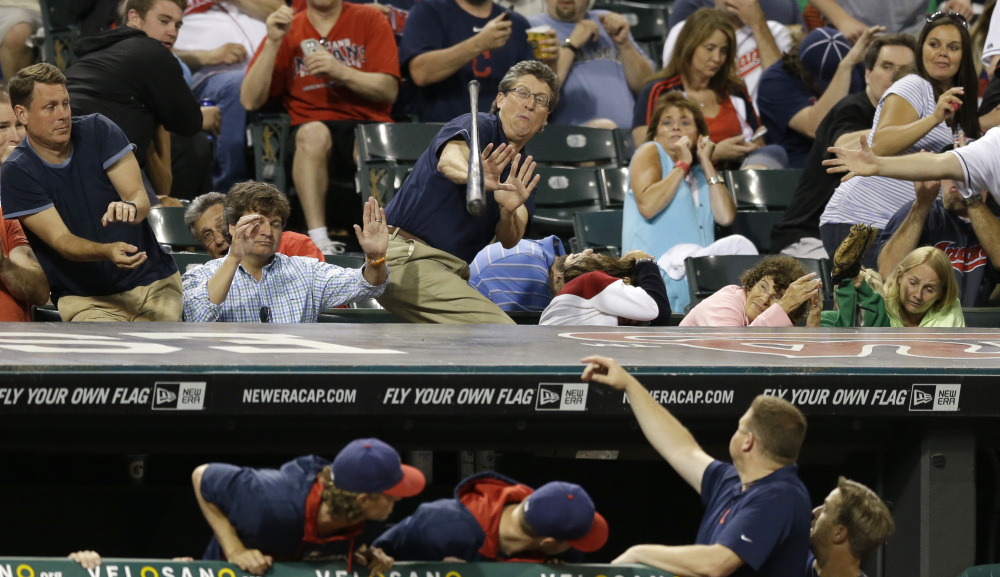 Fans try to dodge a bat that came loose from the hands of Cleveland Indians' Asdrubal Cabrera in the seventh inning of a baseball game against the Boston Red Sox, Tuesday, June 3, 2014, in Cleveland. (AP Photo/Tony Dejak)