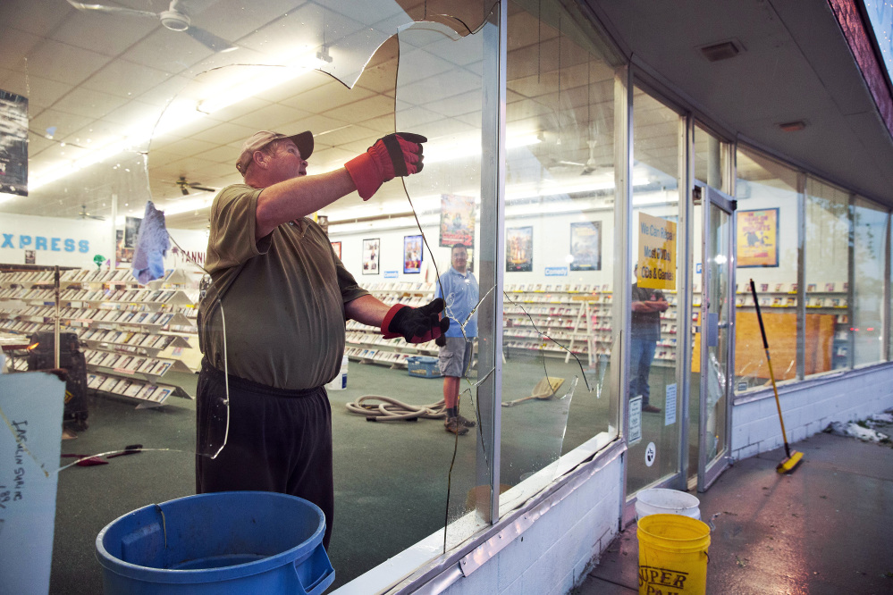 The Associated Press Garry Yanke, the owner of Video Express, cleans up the broken glass at his business in Blair, Neb.