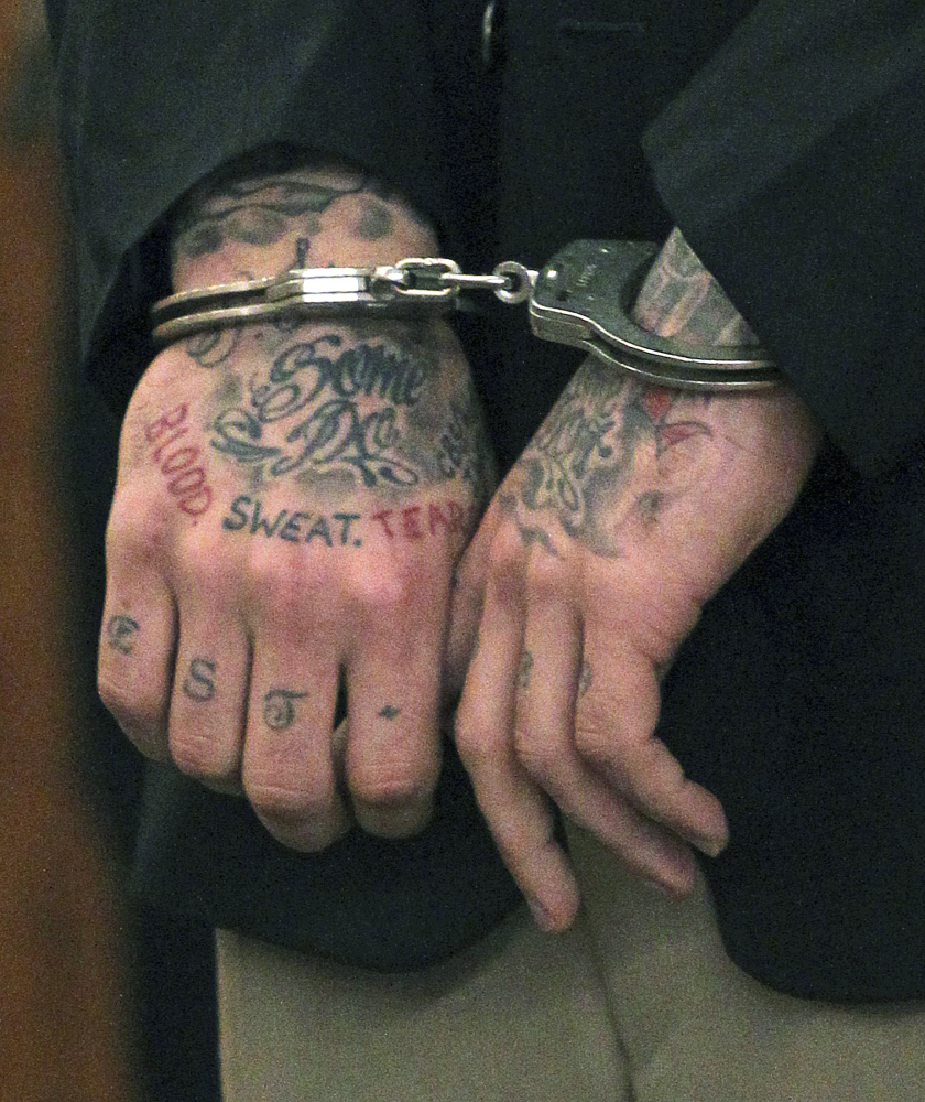 The Associated Press Former New England Patriots player Aaron Hernandez’s tattooed hands are secured with handcuffs as he arrives for his court appearance at Superior Court in Fall River, Mass., in this Dec. 23, 2013, photo. Hernandez is accused of three murders in Massachusetts. Investigators have appealed for information from tattoo artists who inked his right forearm, but won’t say which of Hernandez’s many tattoos prompted their appeal.