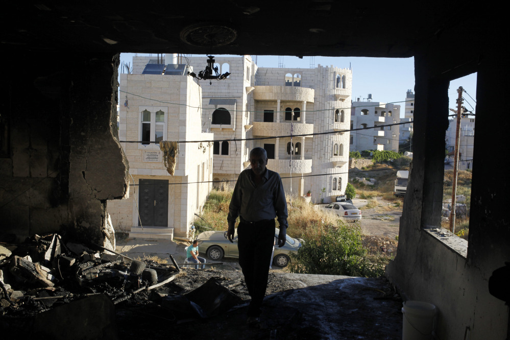 A Palestinian inspects the damaged family home of Amer Abu Aisheh, one of two Palestinians identified by Israel as suspects in the killing of three Israeli teenagers, after it was damaged by the Israeli army in the West Bank city of Hebron, Tuesday, July 1, 2014. Israeli soldiers blew up a door of Abu Aisheh’s home in Hebron early Tuesday, said an Israeli military official. AP photos show extensive damage to one side of the house.
