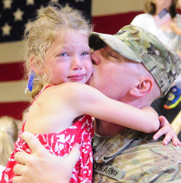 Capt. Brian McClellan of Eliot gets a big hug from daughter Sarah Beth McClellan, 8, after the 133rd Engineer Battalion was dismissed Tuesday at the Augusta Armory. “It feels great to be back,” he said.