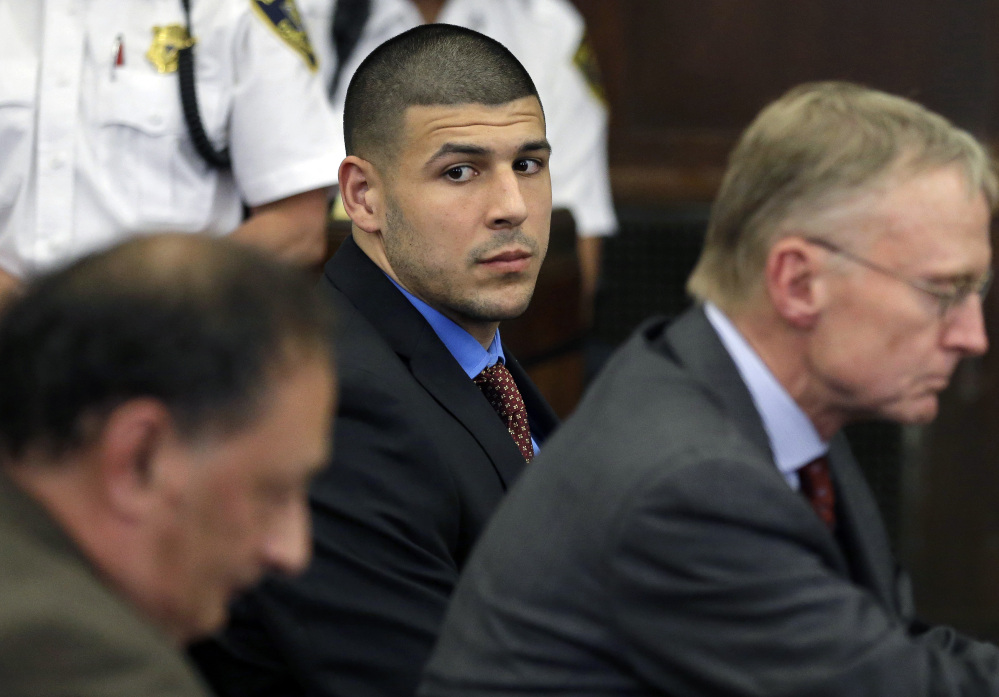 Former New England Patriots football player Aaron Hernandez, center, looks toward defense attorneys James Sultan, left, and Charlie Rankin, right, during a hearing in Suffolk Superior Court in Boston in June.