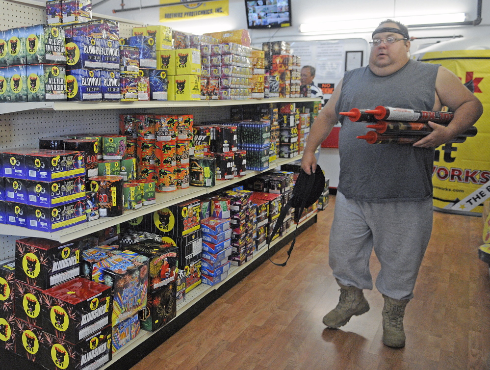 John Bergen of Somerville carries fireworks Tuesday at the Pyro City store in Manchester. Bergen, a self-described professional explosives engineer, said safety is paramount with fireworks.  “It’s up to the individual to keep it safe so we all can enjoy the tradition,” he said. This year, shoppers are looking for lots of colors in their fireworks, one store official said.