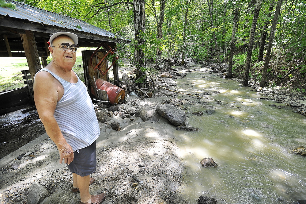 Ted Orino, a resident of 21 years, stands by the brook that changed its direction and filled with rocks and soil in Rumford during storms on Wednesday night. He calculated that 5 inches of rain fell in two hours at his home weather station.