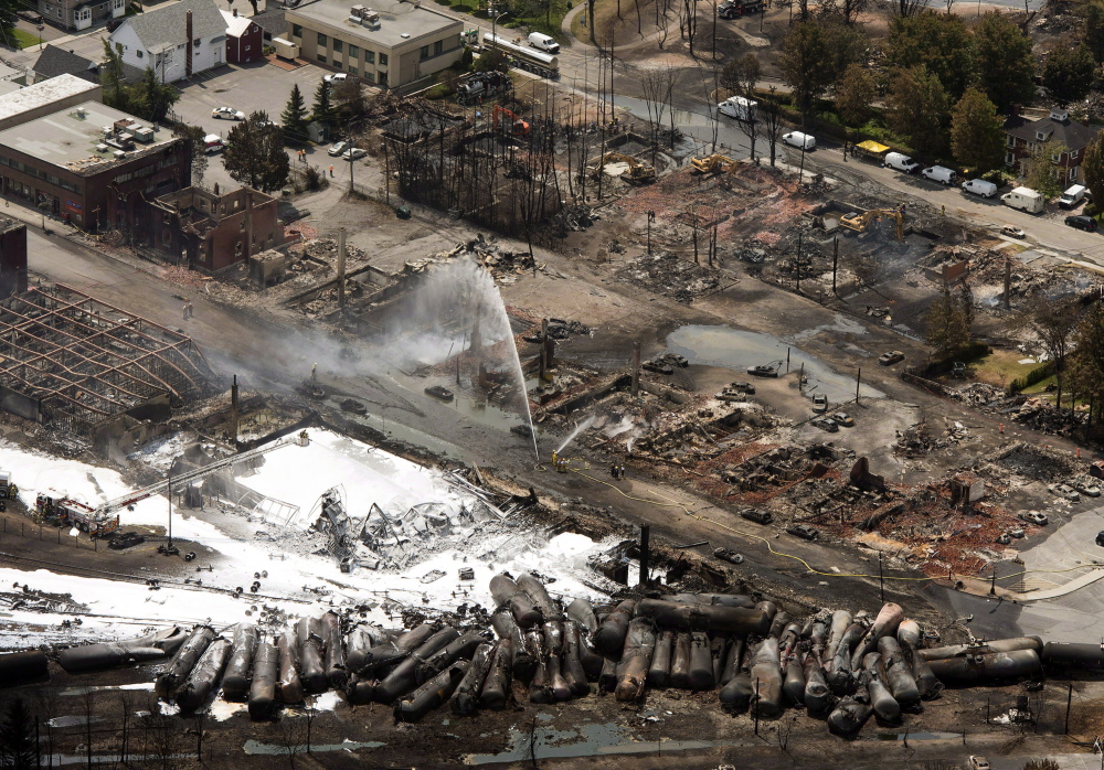 The downtown core is in ruins as firefighters water smoldering rubble in Lac-Megantic, Quebec, on July 7, 2013, a day after a train derailed, igniting tanker cars carrying crude oil.