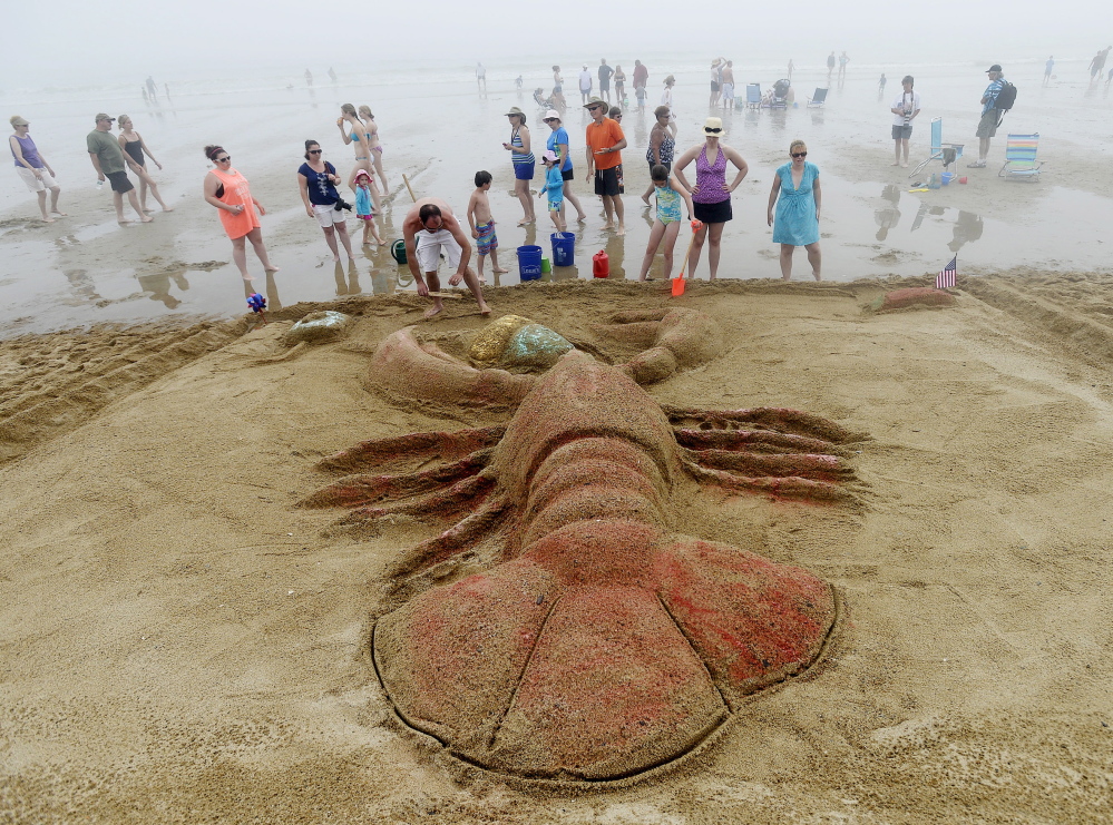 Jason Sargent, front, of Caribou puts the finishing touches on his team’s sand sculpture of a lobster eating an ice cream cone.
