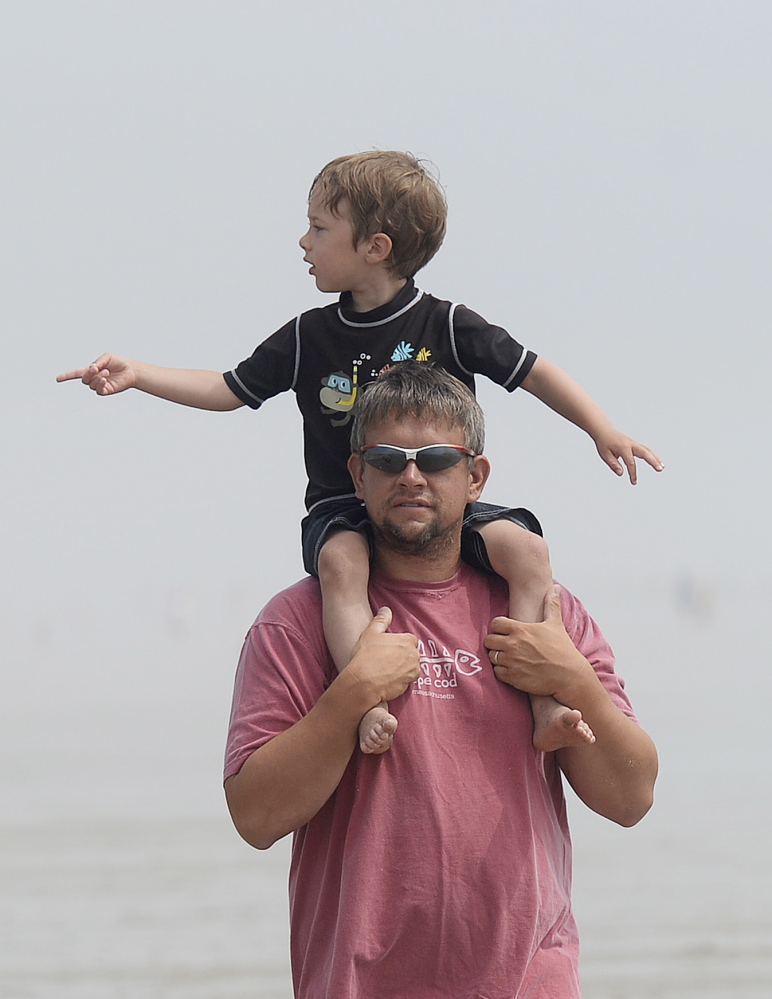 Jason Brown of Barre, Mass., and his son Abraham, 4, look over the sand sculpting competition in Ocean Park on Thursday. More than 60 families participated in the contest.