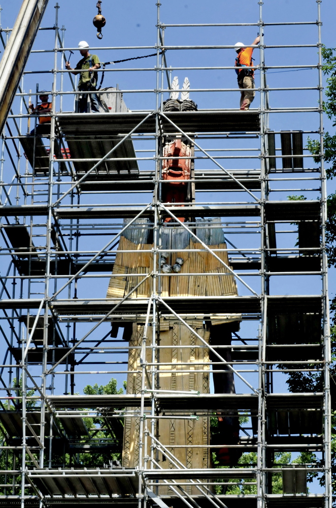 Workers from Seacoast Scaffolding erect scaffolding around the Skowhegan Indian statue for restoration. The arm at left is missing and there are several holes and rotted wood.