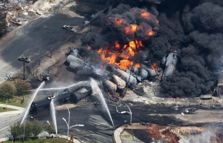 Smoke rises from derailed railway cars carrying crude oil in downtown Lac-Megantic, Quebec, on July 6, 2013. Lac-Megantic still struggles to recover as it marks the disaster’s one-year anniversary.