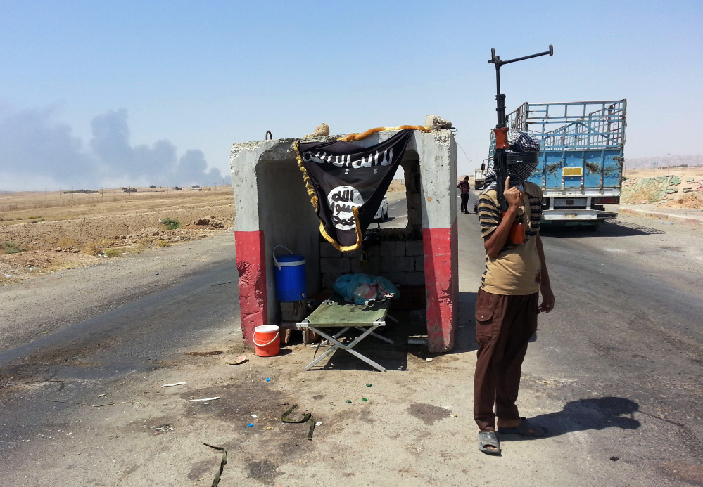 An al-Qaida-inspired militant stands guard last month at a checkpoint north of Baghdad that was captured from the Iraqi army.