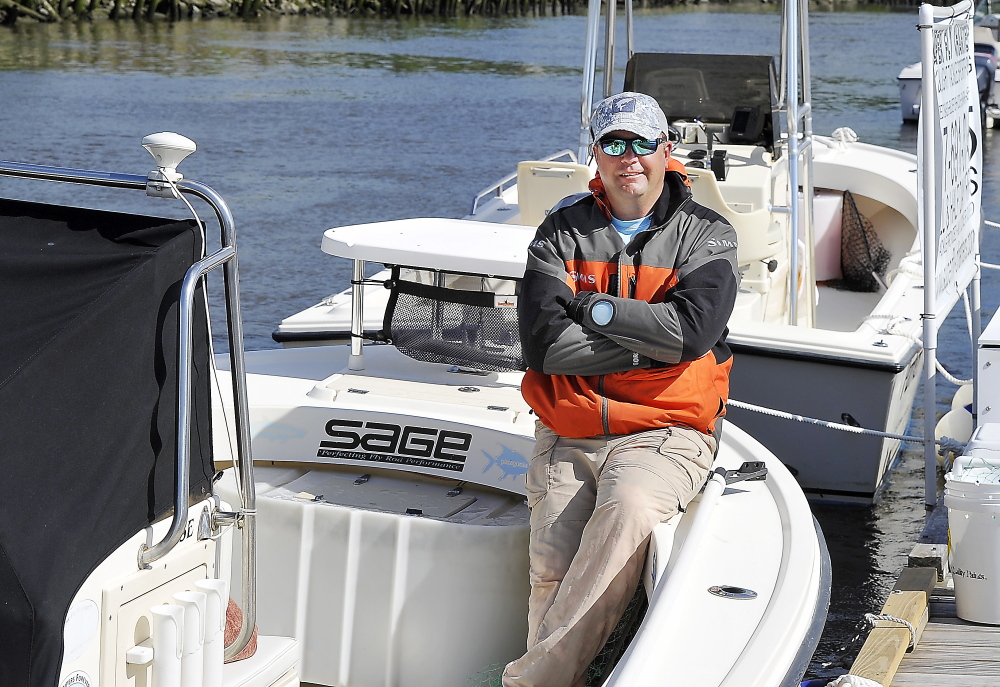 George Harris, a Maine Guide and fishing expert, relaxes on one of his two fishing boats tied up at the Kennebec Tavern Restaurant dock in Bath.