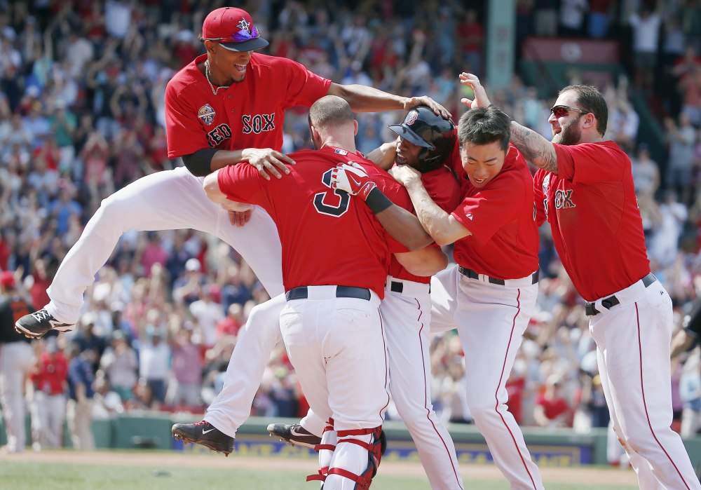 Boston Red Sox’s Jonathan Herrera, center, celebrates his winning RBI single with teammates Xander Bogaerts, left, David Ross (3), Koji Uehara, second from right, and Mike Napoli, right, in the ninth inning of the first game of a doubleheader Saturday against the Baltimore Orioles in Boston. The Red Sox won 3-2.