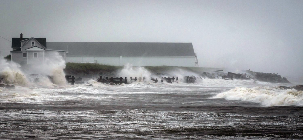 Waves crash against rock embankments that protect the Escuminac road against erosion during Tropical storm Arthur in Escuminac, New Brunswick, Saturday.