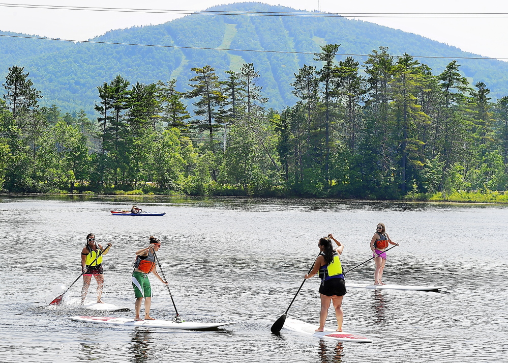 With the ski resort of Mt. Abram serving as a backdrop, paddle boarders from the Sunday River ski resort enjoy the cool waters and beautiful scenery at Round Pond and the adjacent waterways in Greenwood.