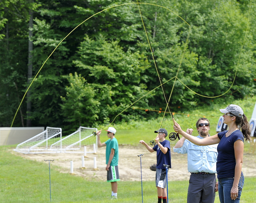Stuart Hickey, a fly casting instructor, helps Jennifer King, right, and her sons Tyler, 15, left, and Bryson, 11, learn how to cast – one of several new offerings at the Sunday River resort in that are part of the new L.L. Bean Outdoors Discovery School there.