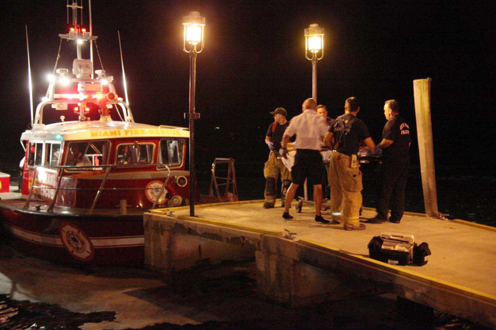 Emergency workers carry an injured person on a stretcher on Friday night after three boats collided near a Miami marina around the end of a fireworks display.