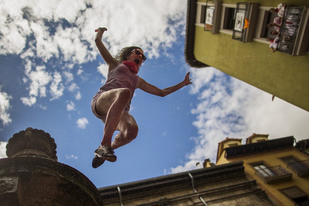A reveler jumps from a fountain onto the crowd below, after the launch of the ‘Chupinazo’ rocket, to celebrate the official opening of the 2014 San Fermin fiestas in Pamplona, Spain, on Sunday.