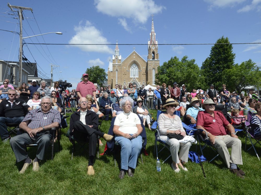 People watch a church service from outside in Lac-Megantic, Quebec, on Sunday on the first anniversary of a train derailment in the small Quebec town that killed 47 people.