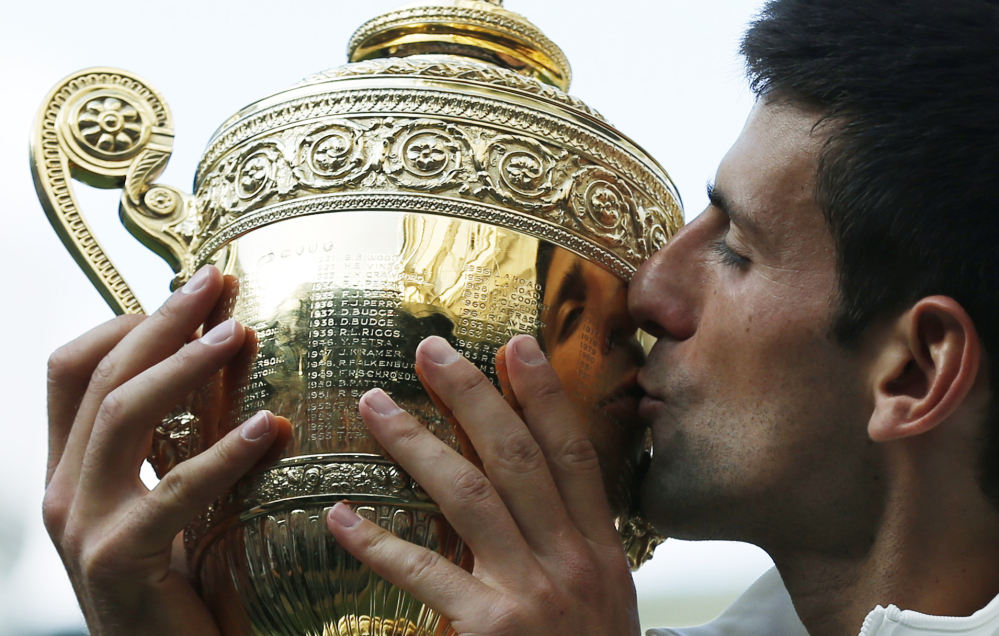 Novak Djokovic kisses the trophy after defeating Roger Federer in the men’s singles final match Sunday at Wimbledon.