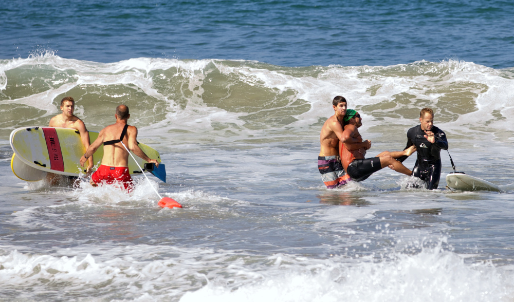 Two men carry a swimmer, second from right, after he was bitten by a great white shark, as lifeguards close in at left in the ocean off Southern California’s Manhattan Beach on Saturday.