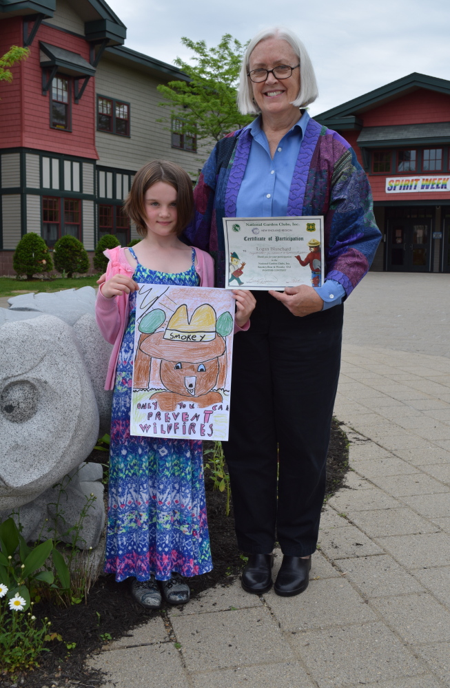 Wells Elementary School second-grader Logan Blanchard and Sandy Brennan, her art teacher, pose with Logan's poster submission, which won a New England competition.