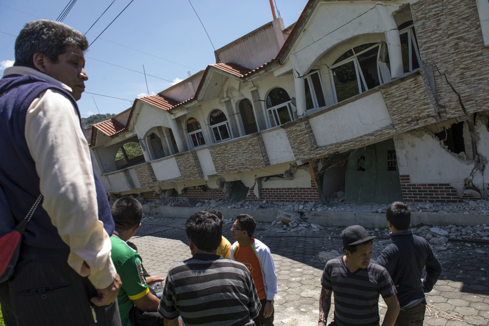 Neighbors gather outside homes that collapsed during an earthquake in San Pedro, Guatemala, on Monday.