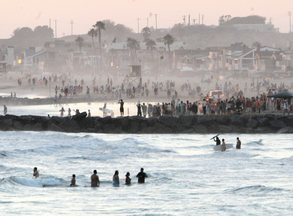 Beachgoers watch as Newport Beach lifeguard boats and lifeguards search for a missing lifeguard on Sunday. Ben Carlson, 32, a Newport Beach lifeguard was finally pulled from the water by fellow lifeguards following a frantic three-hour search.