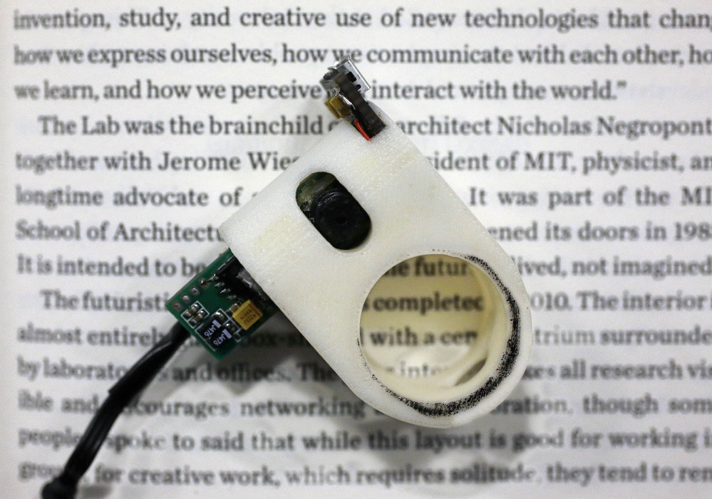 In this Thursday, June 26, 2014 photo, a FingerReader ring lies on a book’s page at the Massachusetts Institute of Technology’s Media Lab in Cambridge, Mass.
